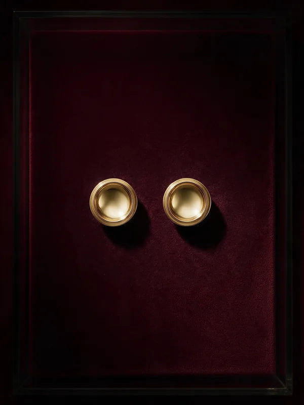 A pair of Patera Earrings in gold on wine velvet