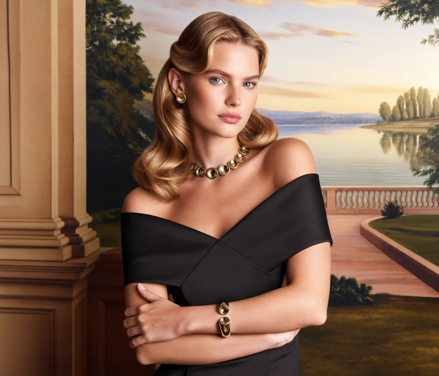 A model in a black dress wearing the Patera Necklace, Earrings and Cuff before a painted lake at sunset