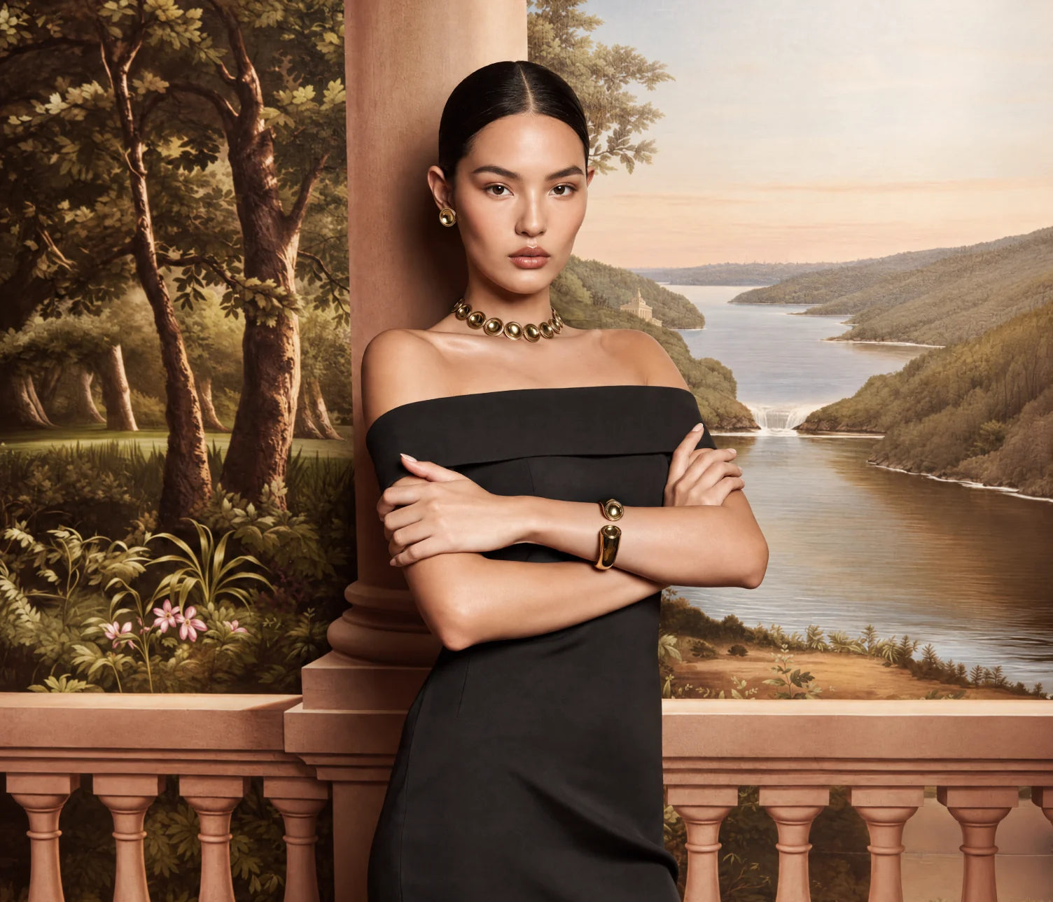 A model in a black dress wearing the Patera Necklace, Earrings and Cuff on a terrace above a painted river valley