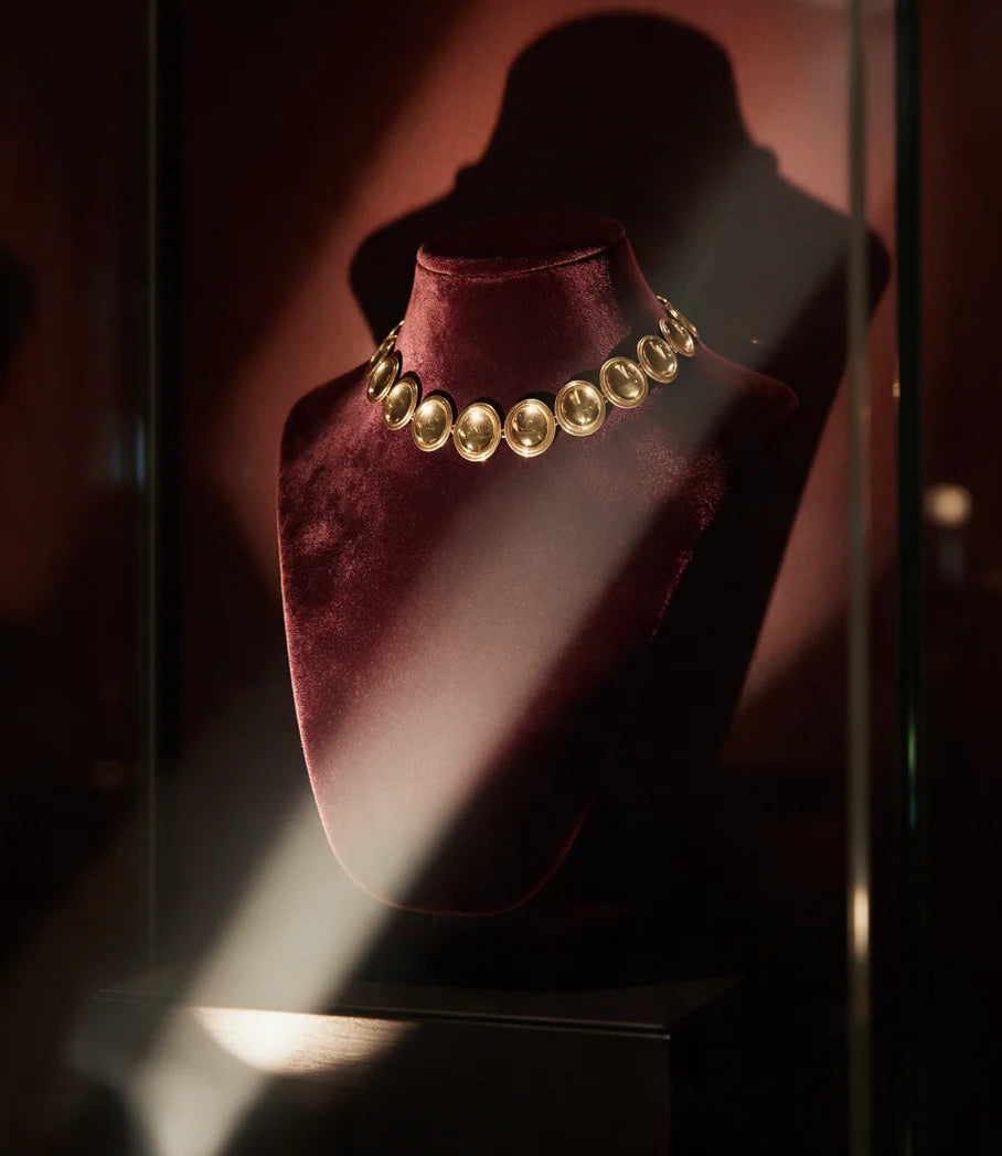 The Patera Necklace in gold on a velvet display bust